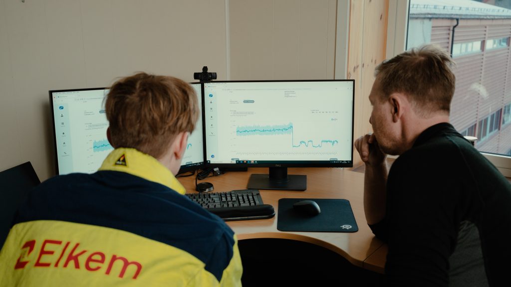 Two workers ensuring Equipment uptime on computer screens.